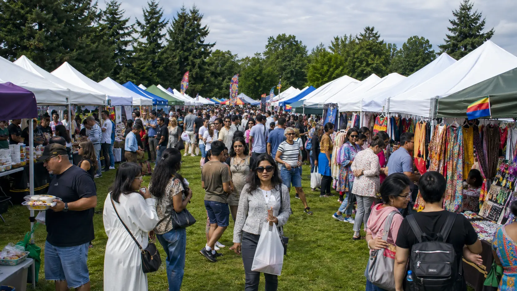 Shoppers browsing clothing, art and crafts along a busy vendor market aisle